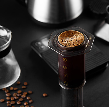 AeroPress on a table with coffee beans